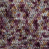 A closeup of a crochet swatch of the Queen City colourway. It is a variegated swatch, with colour shifting quickly between grey, wine purple & grey.